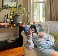 a person sitting on a couch with a book in their lap and a potted plant behind them