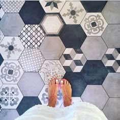 a person standing in front of a wall with hexagonal tiles on the floor