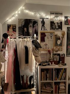 a room filled with lots of clothes and pictures on the wall next to a bookshelf