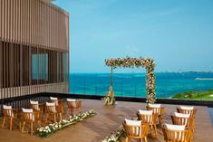 an outdoor ceremony set up with chairs and flowers on the floor, overlooking the ocean