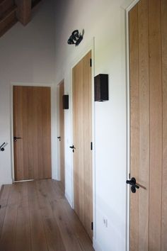 three wooden doors in an empty room with wood flooring and white paint on the walls