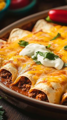 an enchilada dish with meat, cheese and sour cream on the top