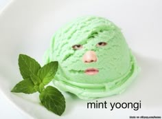 a green face mask sitting on top of a white plate next to a mint leaf