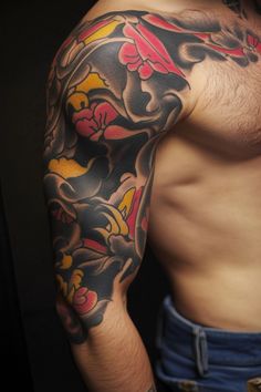 Man with a colorful sleeve tattoo featuring flowers and abstract patterns. Full Arm Sleeve, Tattoo Ideas For Men