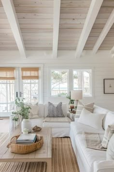 a living room filled with white furniture and lots of wood flooring on the walls