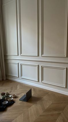 an empty room with wooden flooring and white paneled walls on either side of the wall