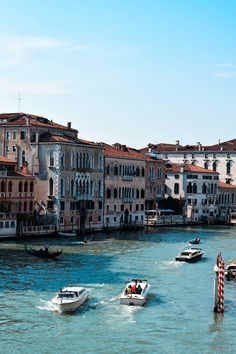 several boats are traveling down the water in front of buildings