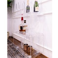 there is a shelf with wine glasses and bottles on it in the corner next to a rug