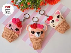 three crocheted ice cream keychains are on a table next to flowers