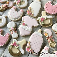 baby shower cookies decorated with pink and white icing on a wooden table next to some gold cookie cutters