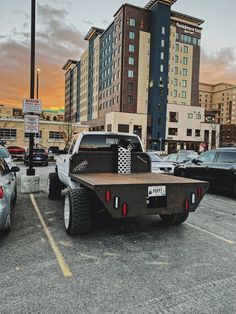 a large truck is parked in a parking lot with other cars and buildings behind it