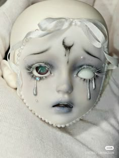 a white doll with blue eyes and makeup on it's face is laying down