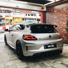 a silver car parked in front of a brick wall