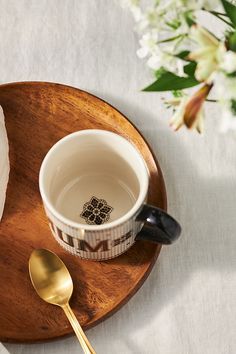 a wooden plate topped with a cup and spoon