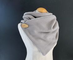 a white mannequin with a gray scarf on it's head and buttons