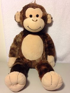 a stuffed monkey sitting on top of a white table next to a wall and towel