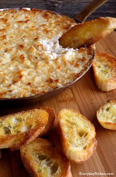 a casserole with cheese and bread sticks on a cutting board next to it