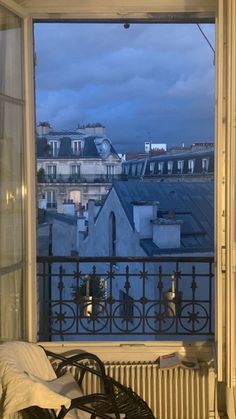 an open window with a view of the city from it's rooftops at dusk