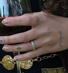 a woman holding a wine glass in her right hand with tattoos on it's fingers