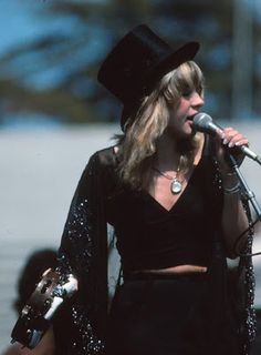 a woman wearing a black hat and holding a microphone