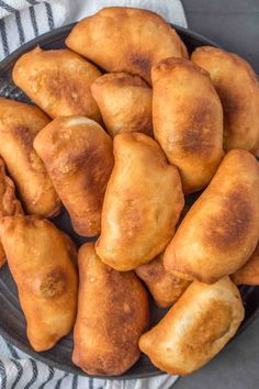 a black plate filled with fried pastries on top of a white and gray towel