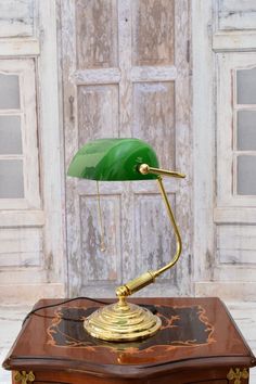 a green desk lamp sitting on top of a wooden table next to a white door