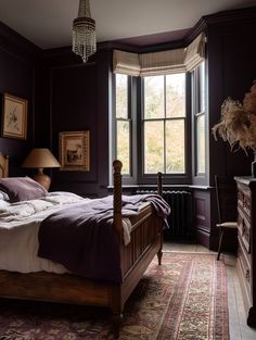 a bed sitting in a bedroom next to a window with a lamp on top of it