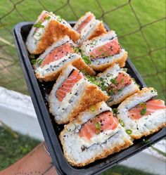 there is a tray with sushi on it and someone holding the tray in their hand