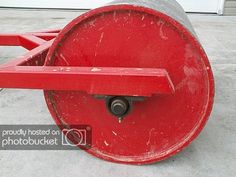 a red metal object sitting on top of a cement floor next to a garage door