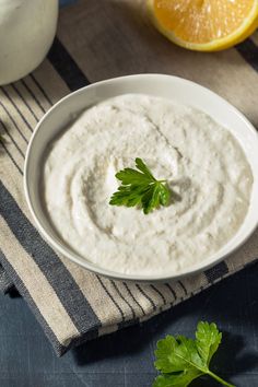 a bowl of dip with parsley in it on a striped napkin next to an orange