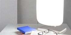 a white lamp sitting on top of a table next to a book and eyeglasses