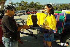 a man standing next to a woman in front of a truck with yellow shirts on it