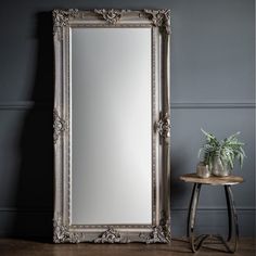 an ornate silver framed mirror next to a small table with a potted plant on it