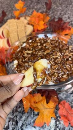 a person spooning some food out of a bowl with leaves on the ground behind it