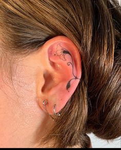 a woman's ear has a tattoo on it