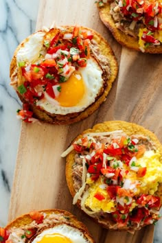 three eggs are on top of bread with toppings and garnished in red peppers