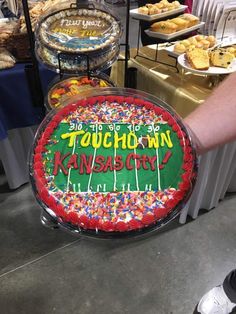 a person holding up a cake with the words touch down on it in front of other desserts