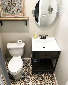 a white toilet sitting next to a sink in a bathroom under a mirror and wooden frame