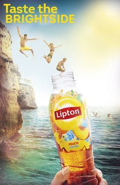 a person holding up a bottle of lipton tea in front of some people jumping into the water