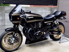 a black and gold motorcycle parked in front of a garage door on the side of a building