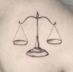 a man's back with a tattoo of two scales on it