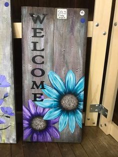 two wooden signs with flowers painted on them and the words welcome written in large letters