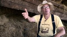 a man in overalls and a cowboy hat pointing at something