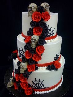 a three tiered cake decorated with red and black sugar roses, skulls and spider webs