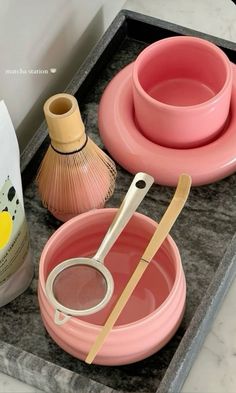 pink dishes and utensils are on a tray