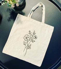 a tote bag sitting on top of a table next to a vase with flowers