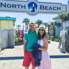 a man and woman standing in front of the entrance to north beach, with their arms around each other