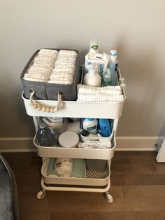 a white cart filled with lots of bathroom items on top of a hard wood floor