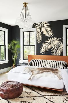 a bedroom with black walls and white bedding, large windows, an animal print rug on the floor