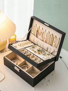 an open jewelry box sitting on top of a table next to a lamp and beads